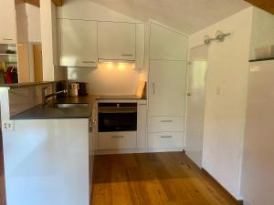 a kitchen with white cabinets and a wooden floor at Haus Anemona in Savognin