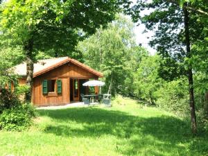 a cabin in the middle of a grassy yard with an umbrella at Chalet en Auvergne -Pêche in Roumégoux +10 photos