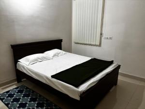 a bedroom with a bed with a black frame and white sheets at Odranest Serviced Apartment in Secunderabad