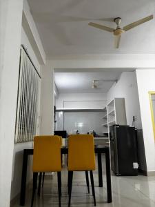 a dining room with a table and two yellow chairs at Odranest Serviced Apartment in Secunderabad +14 photos