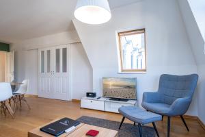 a living room with a blue chair and a tv at Schloss am Meer App 5 in Ahlbeck