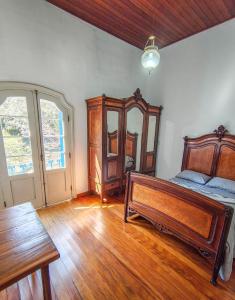 a bedroom with a wooden bed and a mirror at Refúgio Casarão in Passa Quatro