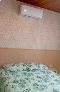 a bedroom with a bed and a air conditioner on the wall at Canto dos pássaros in Volta Redonda