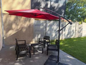 three chairs and a red umbrella on a patio at Les prunelles maison de village de 4 à 8 personnes in Précigné +4 photos