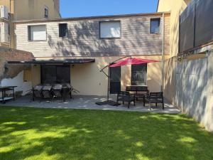 a patio with a table and chairs and an umbrella at Les prunelles maison de village de 4 à 8 personnes in Précigné