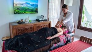 a woman laying on a bed in a room at Sardja Uluwatu in Uluwatu