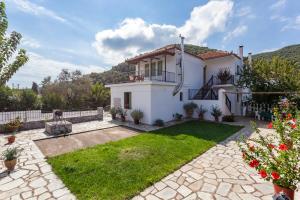 a white house with a yard with a green lawn at Smaragdi Rooms and Studios in Skopelos Town