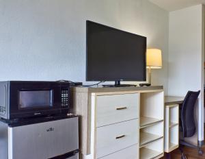 a microwave and a television on top of a cabinet at Magnuson Hotel Jacksonville Downtown in Jacksonville