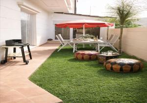 a patio with a table with an umbrella and grass at Azra Luxe villa famille uniquement Family only in Saïdia