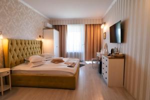 a hotel room with a large bed and a television at Casa Seciu in Ploieşti +7 photos