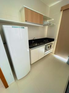 a kitchen with a white refrigerator and a stove at Apartamento Veredas Flat - Rio Quente in Rio Quente