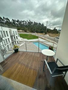 a wooden deck with a table and a pool at Apartamento As T3 Pombal in Pombal