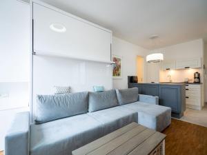 a living room with a blue couch and a kitchen at Quartier 7, App 06 in Ahlbeck