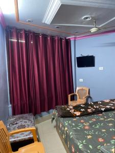 a bedroom with red curtains and a bed and a chair at Friends corner Dharamshala in Dharmsāla