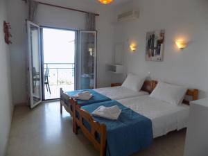 ein Schlafzimmer mit zwei Betten und einer Tür zum Balkon in der Unterkunft Elli Panoramic View appartments in Ýpsos