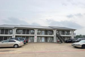 a building with cars parked in a parking lot at Delux Inn Mesquite Near I-30 Dallas in Mesquite