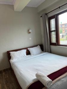 a bedroom with a large bed with a window at Bandipur Samira Hotel & Homestay - your comfort in heart of Bandipur in Bandipur