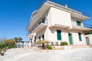 a large white building with green shutters at Cresta Panoramic apartments in Naso