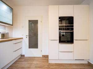 a kitchen with white cabinets and black appliances at Ferienhaus Amica in Heringsdorf +24 photos