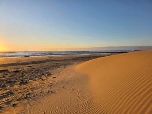 a sand dune on the beach at sunset at Kayser's Keep Self-Catering in Kayserʼs Beach