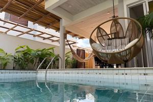 a swimming pool with two hanging chairs and a swing at Refugio de Luxo com Piscina e Jacuzzi em Pipa in Pipa