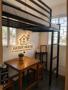 a loft bed with a table and a guest house sign at Bed and Breakfast at PV2NaicCavite in Naic