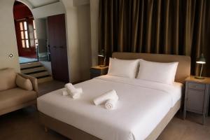 a bedroom with a white bed with towels on it at Galetso Studios by Still Collection in Nikiti