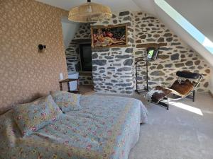 a bedroom with a bed and a stone wall at Gîte Le Cheix d'Arches in Arches