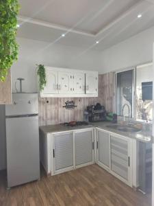 a kitchen with white cabinets and a white refrigerator at Villa Maya House - Cap Zbib in Banī ‘Aţāʼ