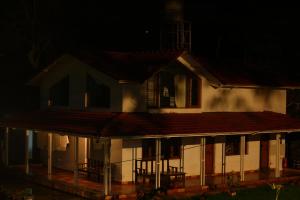 a white house with a porch at night at The Attic at Infinity Valley in Kotagiri