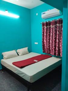 a bedroom with a bed with a blue wall and curtains at D S Villa with swimming pool in Kuilapayam