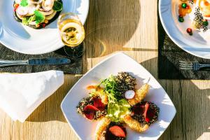 a table with plates of food and a glass of wine at Levante Athletic Resort in Afantou +22 photos