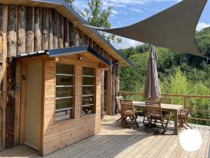 a wooden deck with a table and chairs and an umbrella at Source Nature in Le Mas-dʼAzil
