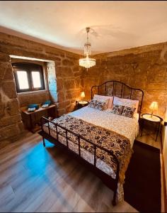 a bedroom with a bed in a stone wall at Vila Adelaide in Campos