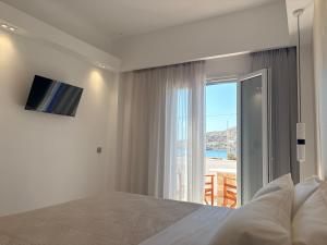 a bedroom with a bed and a large window at Hotel Faros in Ios Chora
