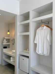 a white bathroom with a white shirt on a shelf at Hotel Faros in Ios Chora +40 photos