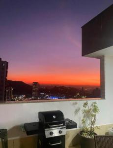 a grill on a balcony with a sunset view at Cobertura Espetacular no Belvedere com Jacuzzi in Belo Horizonte