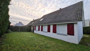 a white house with red doors and a yard at La désirée in Blangy-sur-Bresle
