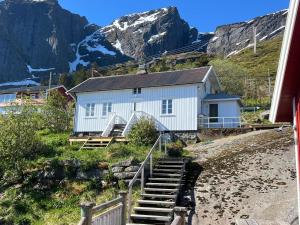 a white building with stairs in front of a mountain at Reine Harbour Cabins in Moskenes
