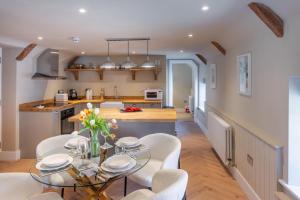 a kitchen and dining room with a glass table and chairs at 16 Ulph Place in Burnham Market +13 photos