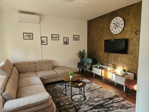 a living room with a couch and a clock on the wall at Kuća za odmor Širok šor in Vukovar