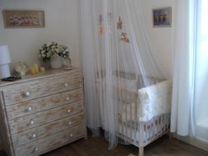 a bedroom with a crib and a dresser with at Chez Julia in Puycelci