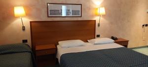 ein Schlafzimmer mit einem Bett und zwei Wandlampen in der Unterkunft Classic Hotel Tulipano in Terni