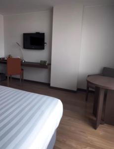 a room with a bed and a table and a tv at Hotel Estelar El Cable in Manizales