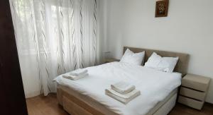 a bedroom with a white bed with towels on it at VLC Apartment in Bucharest