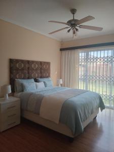 a bedroom with a large bed with a ceiling fan at Buliso Homestay in Amsterdamhoek