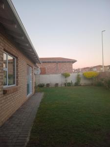 a backyard of a house with a grass yard at Buliso Homestay in Amsterdamhoek