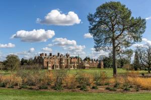 an old mansion in a field with a tree in the foreground at La Retraite in Wolferton