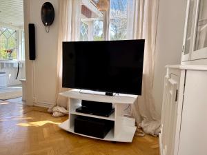 a flat screen tv on a white stand in a living room at Vallevägen Country Retreat - Private Pond, Fireplace & Nature in Öglunda