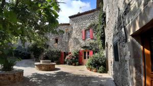 an old stone building with red windows and a courtyard at Maison - Le Petit Bussac in Aigne